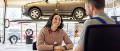 Woman sitting at dealership talking to man