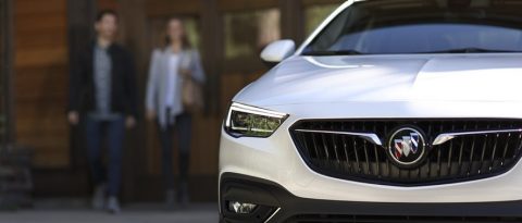 Pareja caminando hacia un vehículo utilitario deportivo (SUV) Buick estacionado en primer plano