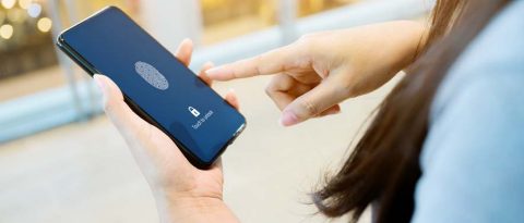 A woman holding a cell phone with a security lock on it