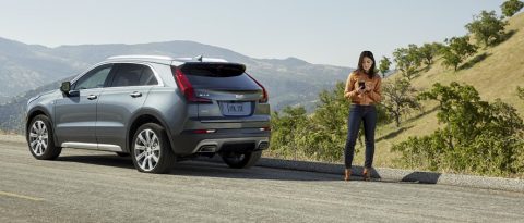 Woman on her phone next to her car on the side of the road