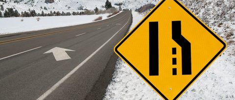 Merge left sign on a wintery mountain road