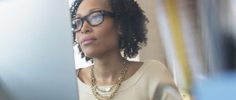 Woman with black-framed glasses researching simple interest on her laptop.